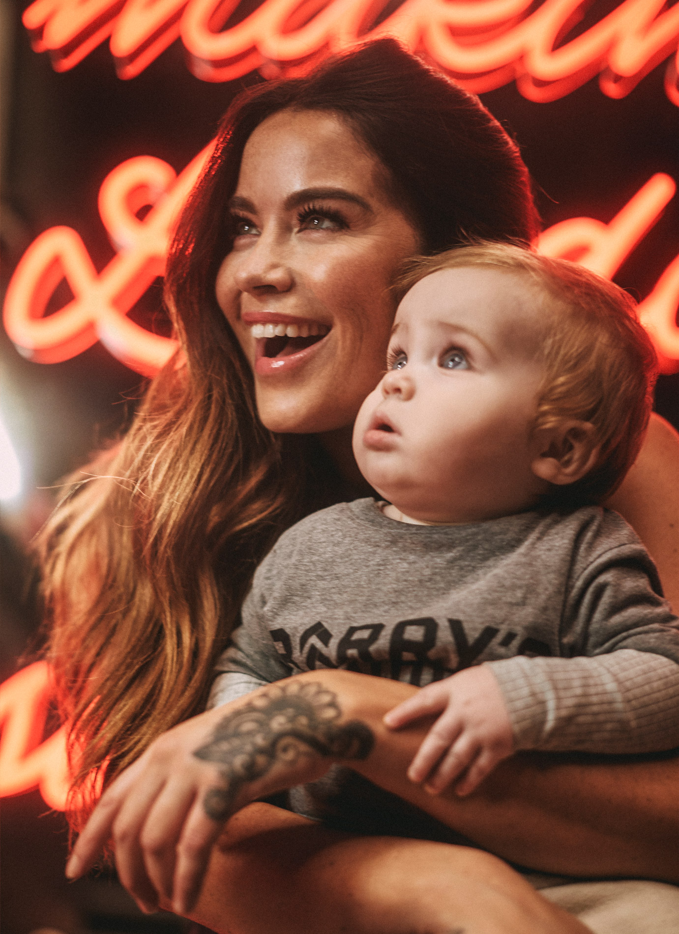 glorious barrys robbo mum holding baby parker in front of neon light portrait